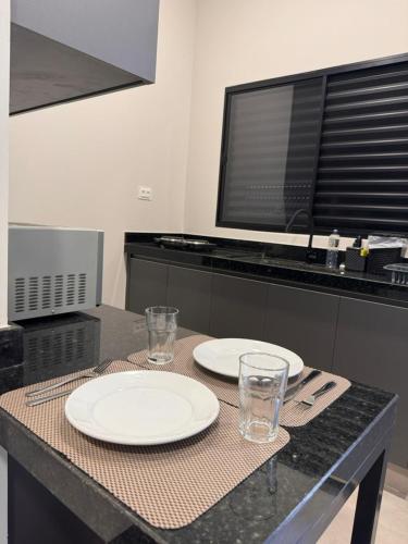 a table with two plates and glasses on it at Studios Soho Bongiovani in Presidente Prudente
