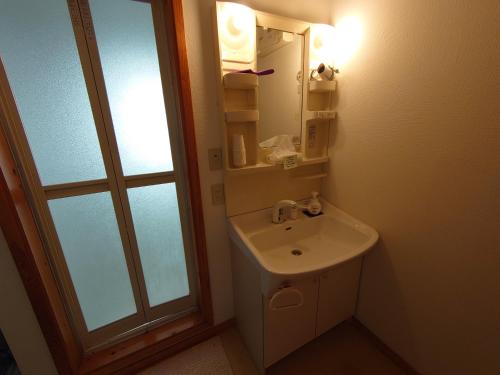 a bathroom with a sink and a mirror at ゲストハウス樹舎 in Minami-jūichijō