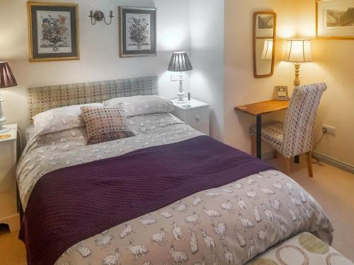 a bedroom with a bed and a desk and a chair at Lilac Cottage in Redmire