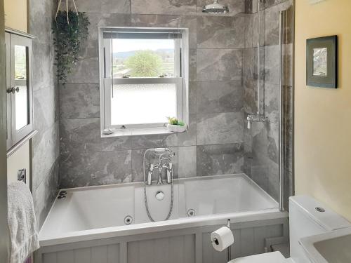 a bath tub in a bathroom with a window at Lilac Cottage in Redmire