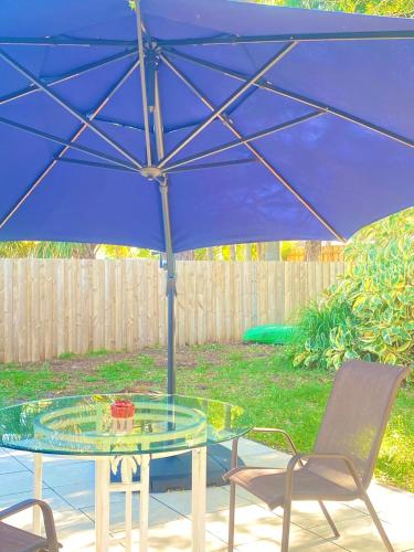 a blue umbrella over a glass table and chairs at Cozy Studio only 10 minutes by car of Siesta Key in Sarasota