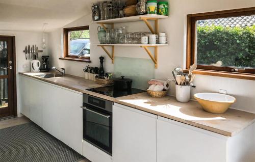 una cucina con armadi bianchi e piano di lavoro di 2 Bedroom Beach Front Home In Rnde a Rønde