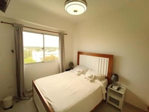 a bedroom with a white bed and a window at Apartamento Marla Comodo y cerca del aeropuerto in Santo Domingo