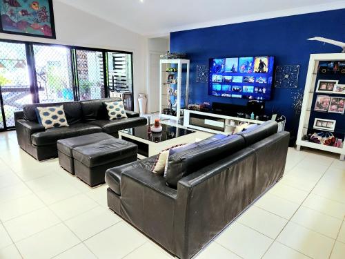 a living room with black leather furniture and a flat screen tv at Island Room in Horseshoe Bay on Magnetic Island in Horseshoe Bay
