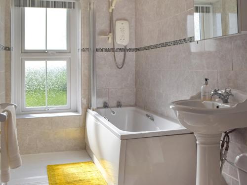 a white bathroom with a sink and a tub and a sink at Gymmin House in Pendine