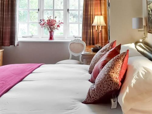 ein Schlafzimmer mit einem Bett mit Kissen und einem Fenster in der Unterkunft The Lodge in Llangelynin