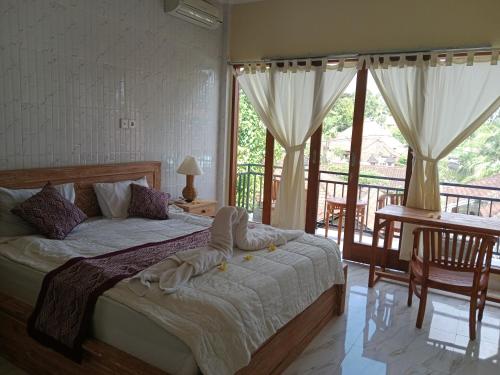 a bedroom with a bed and a balcony at SUNRISE HOUSE in Ubud