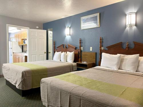 ein Hotelzimmer mit 2 Betten und blauen Wänden in der Unterkunft Coronada Inn & Suites in St. George