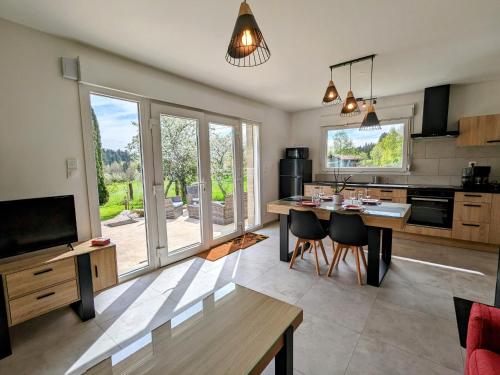 une cuisine avec une table et une salle à manger dans l'établissement Maison neuve et paisible avec étang privé, terrasse et randonnées aux portes du Pays de Salm - FR-1-589-635, à Moyenmoutier