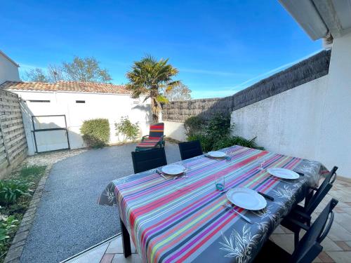 une table avec un tissu de table rayé sur une terrasse dans l'établissement Maison Cosy Type 2 avec Patio Paisible, Proche Centre et Commerces – 3 Couchages - FR-1-231-322, à Bretignolles-sur-Mer