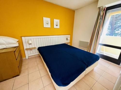 - une chambre avec un lit bleu et un mur jaune dans l'établissement 2 pièces avec terrasse, piscine chauffée, proche plage et port - FR-1-723-152, au Cap d'Agde