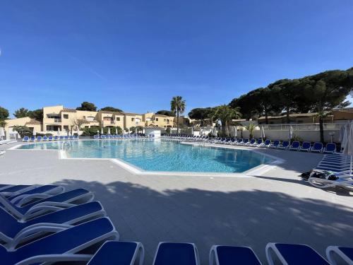 - une grande piscine avec des chaises bleues dans un complexe dans l'établissement 2 pièces avec terrasse, piscine chauffée, proche plage et port - FR-1-723-152, au Cap d'Agde