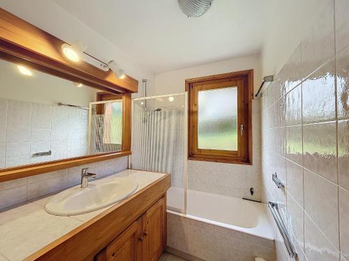 une salle de bain avec un lavabo, une baignoire et un miroir dans l'établissement Appartement Mont Blanc : 2 chambres, terrasse, parking et équipements modernes - FR-1-560-131, à Demi-Quartier