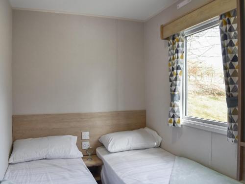 2 Betten in einem kleinen Zimmer mit Fenster in der Unterkunft Forest View 