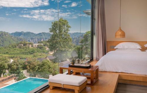 una camera con un letto e una grande finestra con piscina di Avatar Mountain Resort a Zhangjiajie