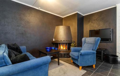 a living room with two blue chairs and a fireplace at 2 Bedroom Cozy Apartment In Hemsedal in Hemsedal