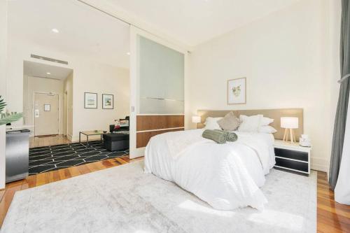a bedroom with a large white bed with a large window at Kiwiana Suite - Auckland CBD - rooftop pool in Auckland
