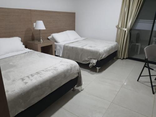 a hotel room with two beds and a chair at HOTEL MELAO in Palmira