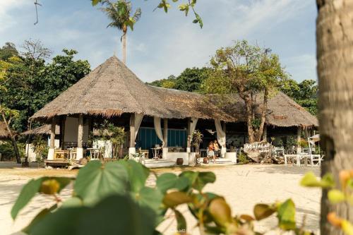 un bâtiment avec un toit de paille, des tables et des chaises dans l'établissement Mayalay Resort-Green Hotel, à Ko Ngai