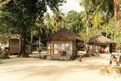a couple of huts with palm trees in a village at Mayalay Resort-Green Hotel in Ko Ngai