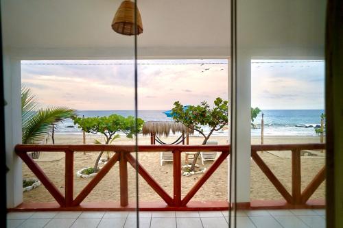 a room with a view of the beach from a window at Casuarinas del Mar Chalet Playa Caballito de Mar in Canoas De Punta Sal