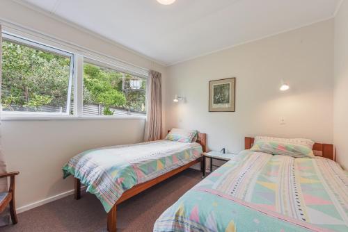 two beds in a room with a window at Sunny Seaview House 5 minute walk to town in Picton
