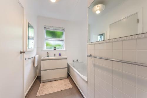 a bathroom with a tub and a sink and a mirror at Sunny Seaview House 5 minute walk to town in Picton