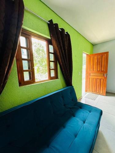 eine blaue Couch in einem grünen Zimmer mit Fenster in der Unterkunft APTO Mobiliado Aconchegante Serra Cantareira Cod 1 in Caieiras