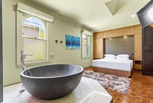 a bathroom with a large bath tub and a bed at A Luxury Space with Playstation in Darling Harbour in Sydney