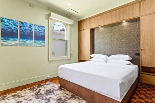 Un dormitorio con una gran cama blanca y una ventana en A Luxury Space with Playstation in Darling Harbour en Sídney