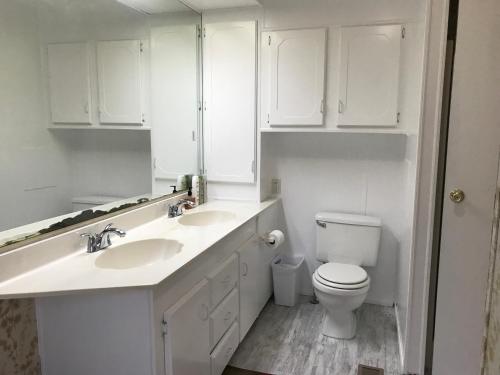 a white bathroom with two sinks and a toilet at Green Cabin in Midpines in Midpines
