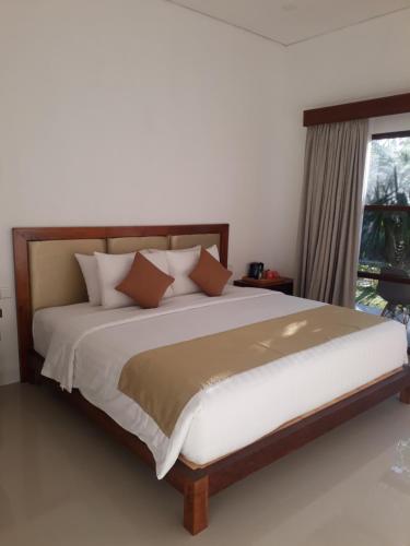 a large bed in a bedroom with a window at Maha di Nusa Lembongan in Nusa Lembongan