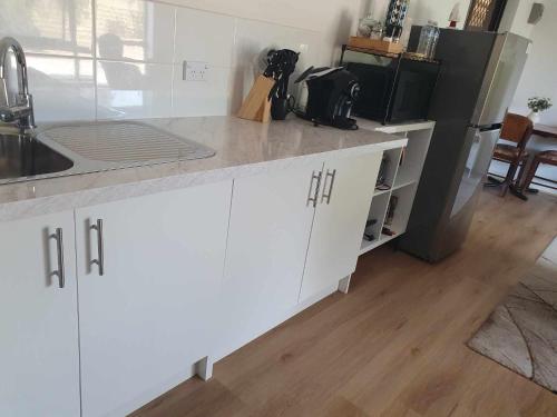 a kitchen with white cabinets and a black refrigerator at Tranquil Studio Apartment Just 3km from Port Pirie in Port Pirie