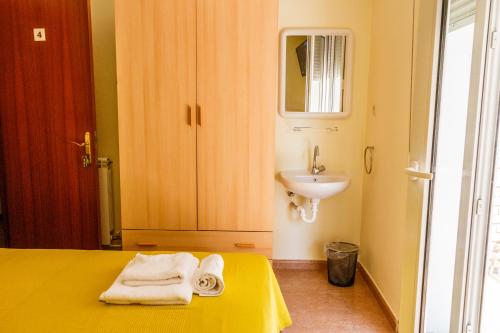 baño con cama amarilla y lavamanos en Pension Teresa, en Calahorra