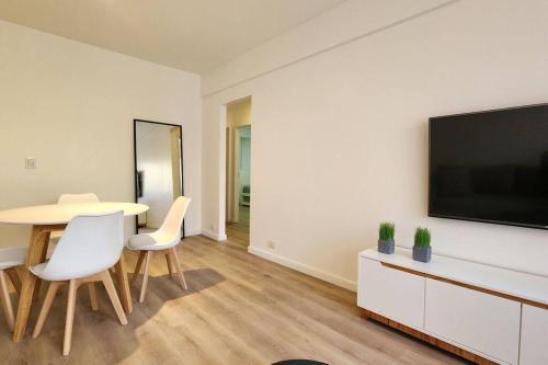 un salon avec une table et une télévision sur un mur dans l'établissement Departamento 3 ambientes., à Buenos Aires