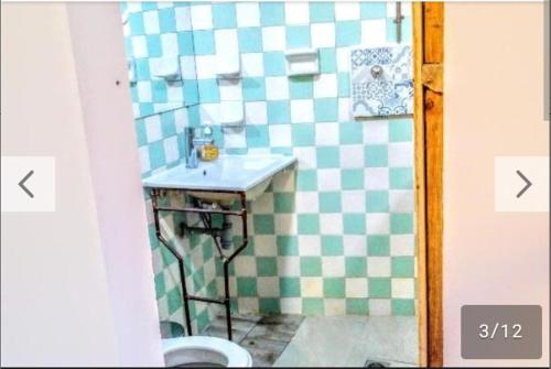 La salle de bains est pourvue d'un lavabo et d'un mur en damier. dans l'établissement VIEJA ADUANA HOSTAL, à Zipaquirá