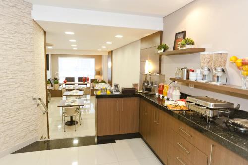 a large kitchen with a counter and a cafeteria at Hotel Sol By MRHotelaria in Curitiba