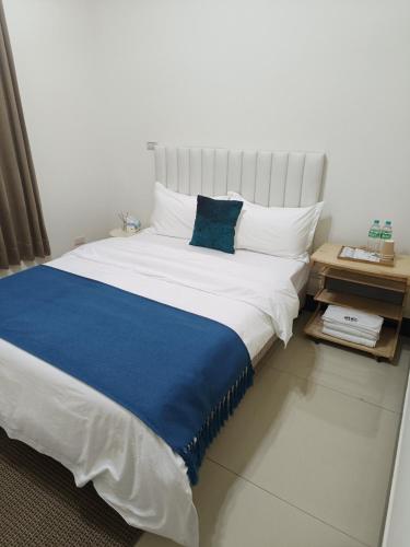 a bedroom with a large white bed with a blue blanket at 玥熙民宿 in Jinhu