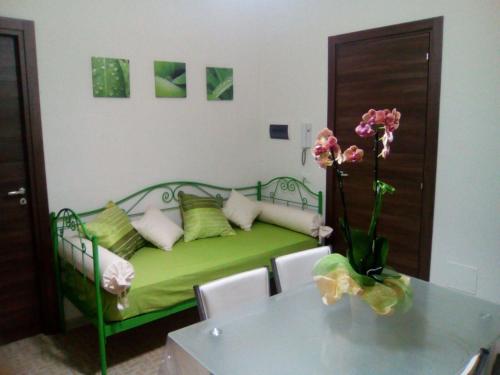 Zimmer mit einem grünen Bett, einem Tisch und Blumen in der Unterkunft Studio für 3 Personen ca 40 qm in Alcamo, Sizilien Nordküste von Sizilien in Alcamo