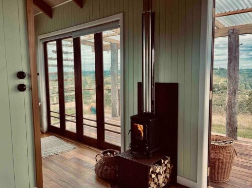 a room with a woodburning stove on a porch at Romantic hilltop hideaway - Skyview Cottage in Dairy Flat