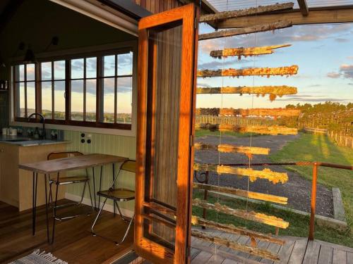 une cuisine et une salle à manger avec une grande fenêtre en verre dans l'établissement Romantic hilltop hideaway - Skyview Cottage, à Dairy Flat