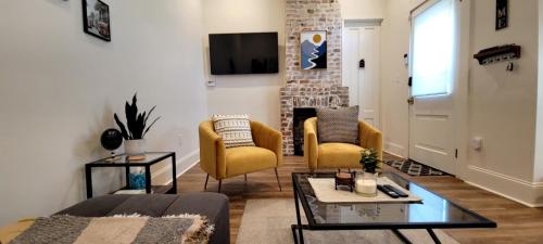 a living room with yellow chairs and a fireplace at Entire Spacious Vacation Home - 1 mile to all Attractions in New Orleans
