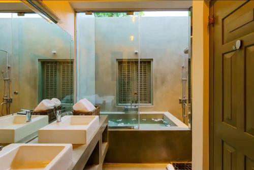 a bathroom with two sinks and a tub and a mirror at Angam Suites Colombo in Sri Jayewardenepura Kotte