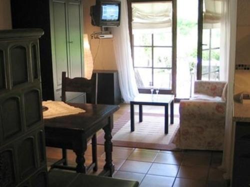 a living room with a table and a chair and a television at Ferienwohnung in Horben mit Großem Garten in Horben