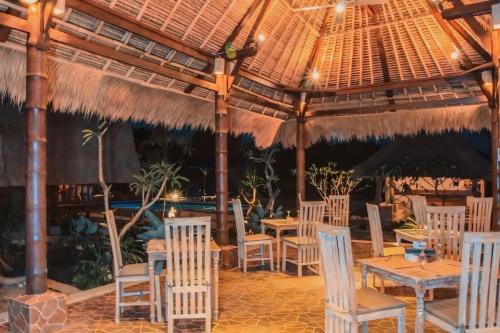un restaurant avec des tables et des chaises sous un toit dans l'établissement Harta Lembongan Villas, à Nusa Lembongan