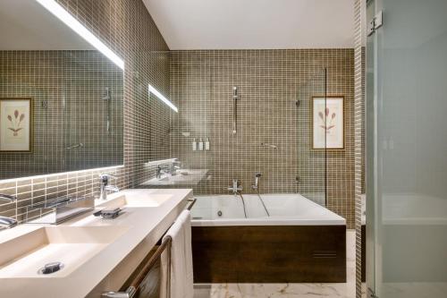 a bathroom with two sinks and a tub and a shower at Hotel Palacio del Retiro, Autograph Collection in Madrid