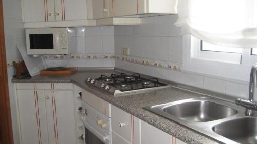 a kitchen with a sink and a stove top oven at Beach Apartment Minerva in Port d'Alcudia