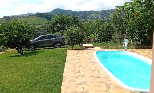 une voiture garée à côté d'une piscine dans une cour dans l'établissement Recanto São Gabriel Socorro/SP chácara com linda Vista, à Socorro
