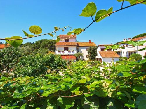 un edificio bianco con tetti rossi dietro alcuni alberi di Ferienwohnung für 5 Personen ca 70 qm in Fažana, Istrien Istrische Riviera a Valbandon