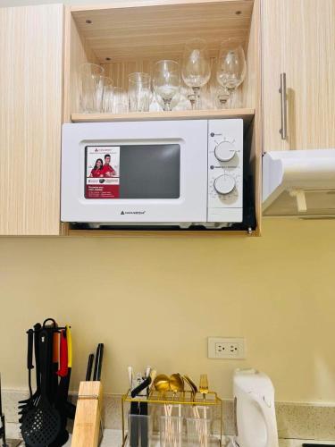 a microwave in a kitchen with wine glasses at Condo in Davao City Near Airport (Seamaster Staycation II) in Davao City